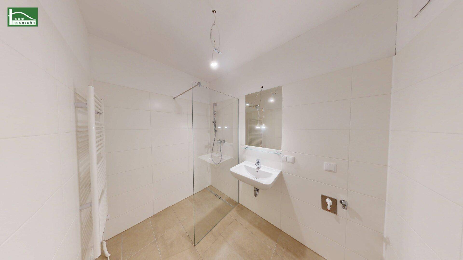 Modernes Badezimmer mit ebenerdiger Dusche, Waschbecken und Handtuchheizkörper.
