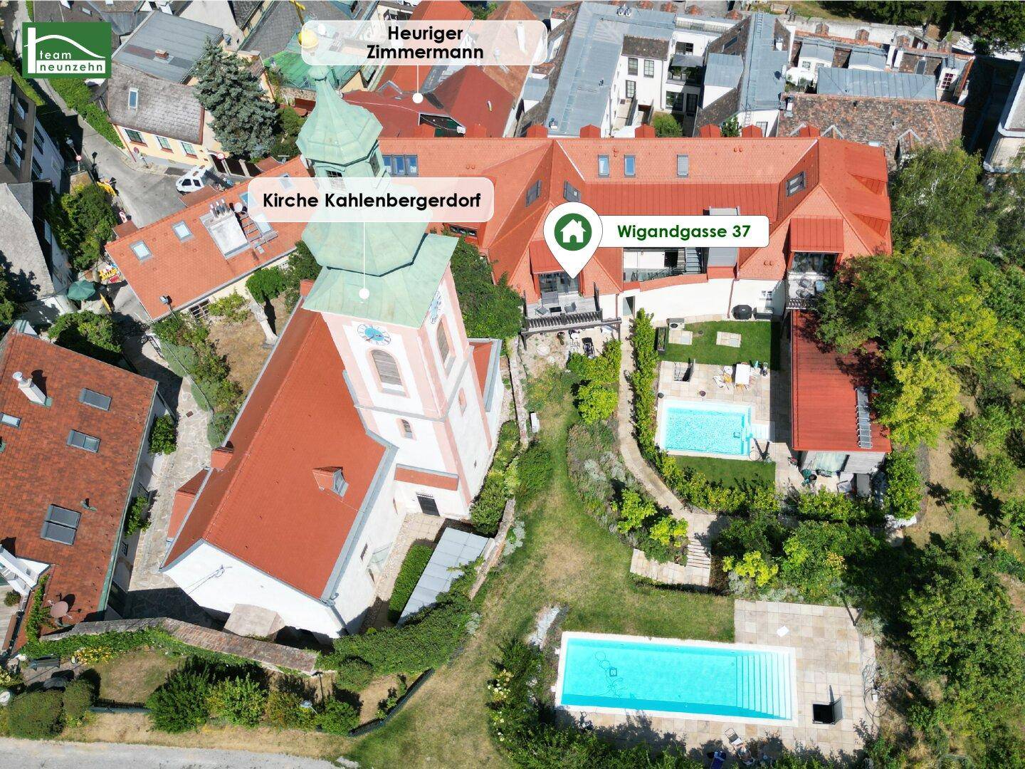 Luftaufnahme eines Anwesens mit zwei Pools, weitläufigem Garten und Blick auf die umliegende Landschaft und Kirche.