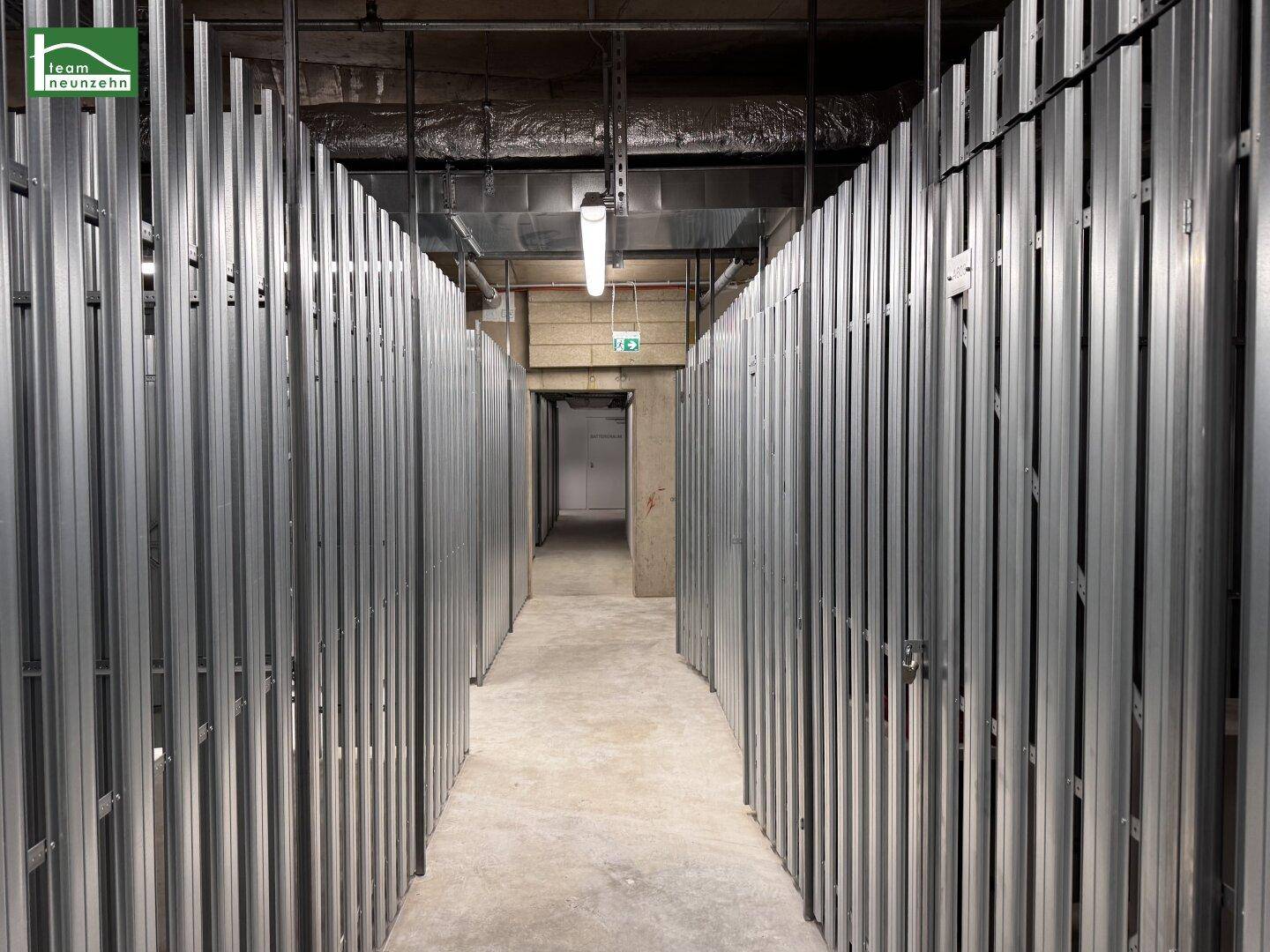 Kellerabteilbereich mit individuellen Lagereinheiten aus Metallgittern in einem modernen Gebäude.