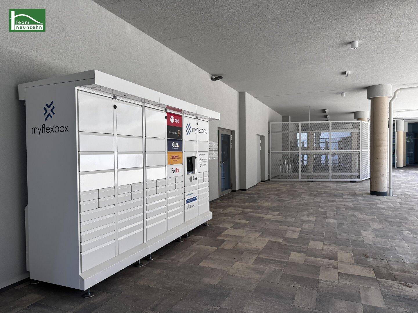 Moderne Paketstation im Eingangsbereich eines Gebäudes, mit Fahrradabstellplätzen im Hintergrund.
