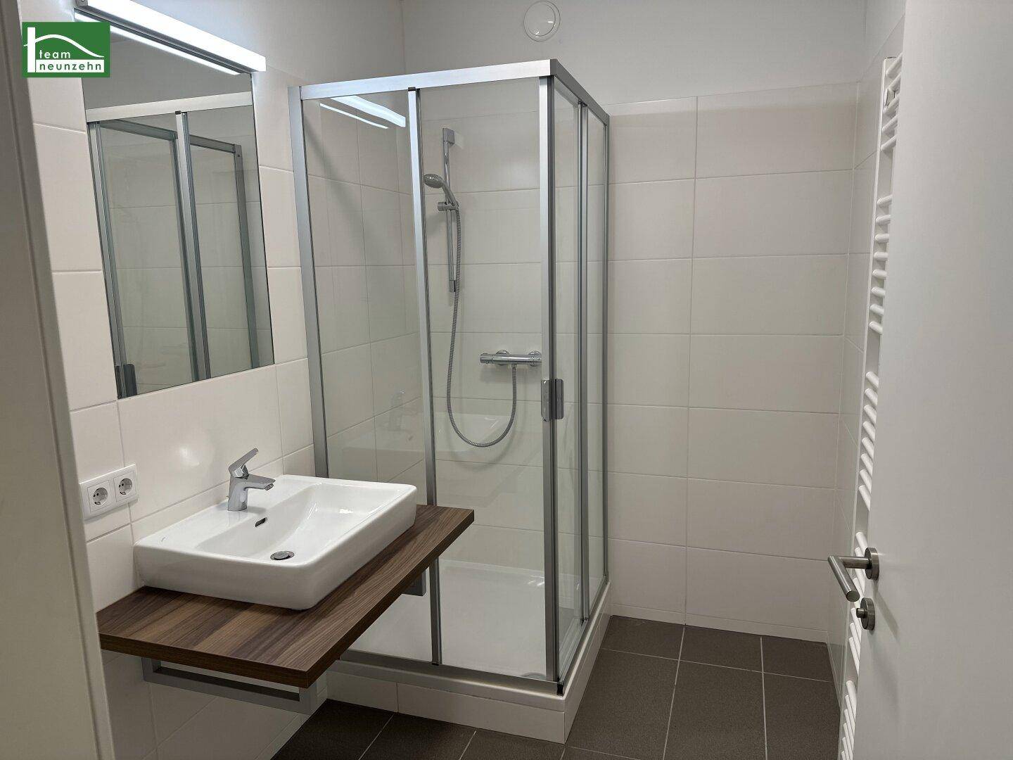Modernes Badezimmer mit Duschkabine, Einzelwaschbecken und weißen Fliesen.