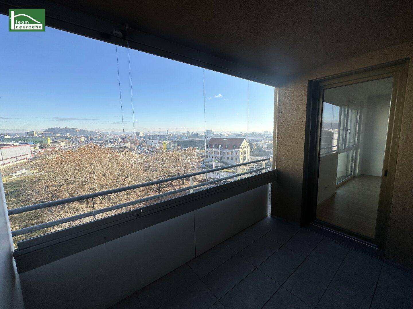 Sonniger Balkon mit Panoramablick über die Stadt und umliegende Gebäude.