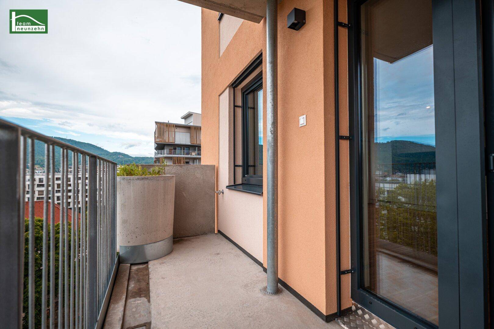 Kleiner Balkon mit Metallgeländer und Blick auf die Stadt und die umliegenden Hügel.