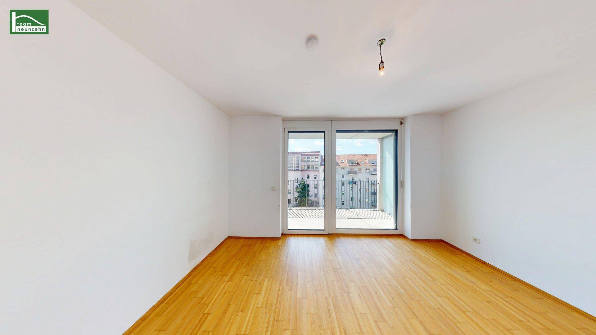 Heller Raum mit Holzboden und Zugang zu einem Balkon, ideal für Wohnzwecke.