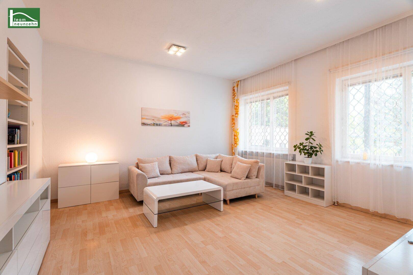 Helles Wohnzimmer mit hellem Parkettboden, beigem Ecksofa und modernen weißen Möbeln.