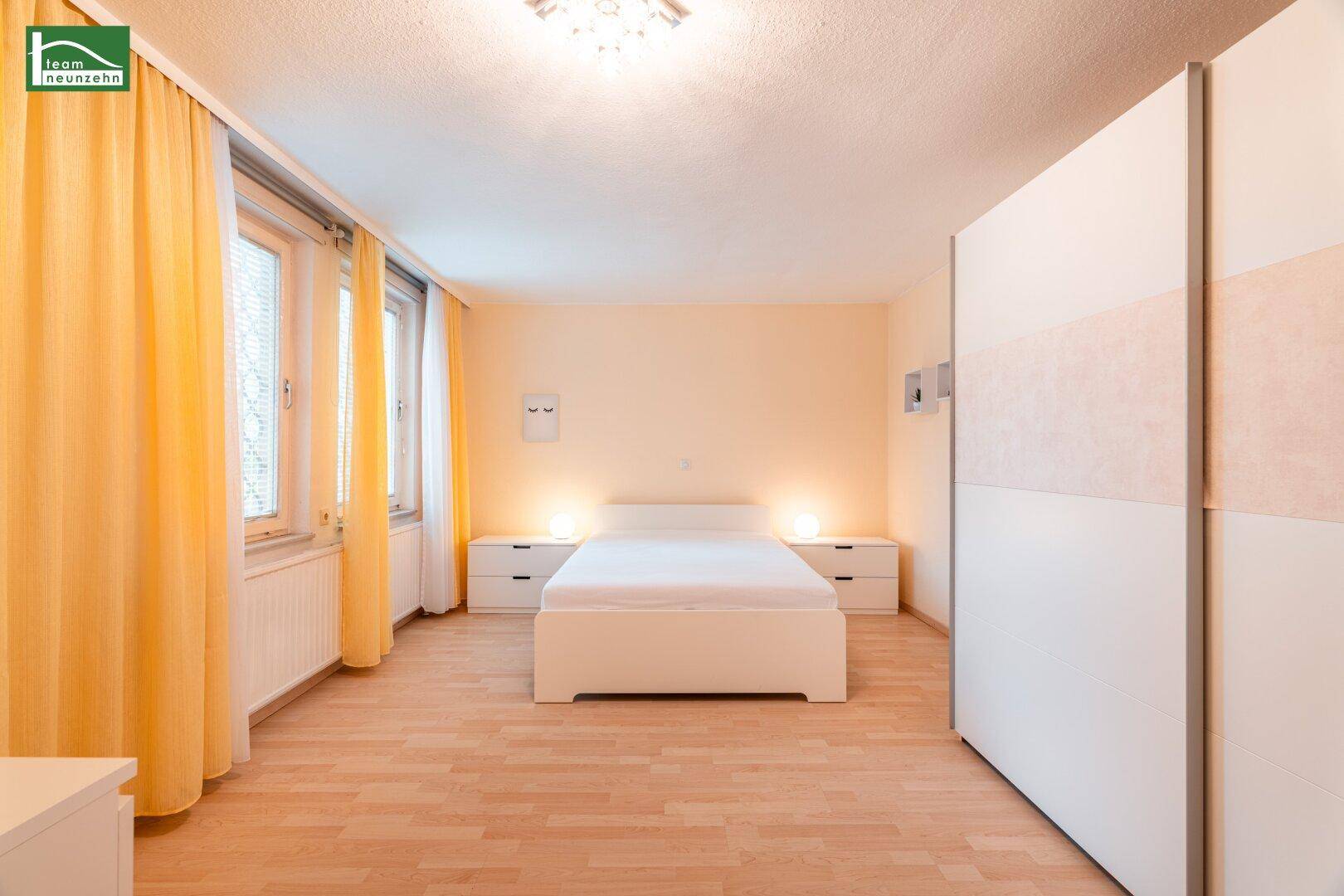 Helles Schlafzimmer mit Doppelbett, weißen Nachttischen und großem Kleiderschrank.
