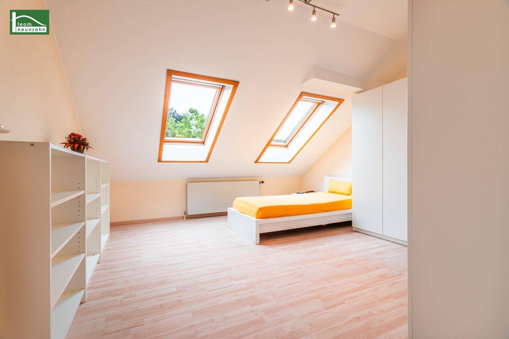 Dachgeschoss-Schlafzimmer mit Schrägdach, Dachfenstern und hellem Parkettboden.