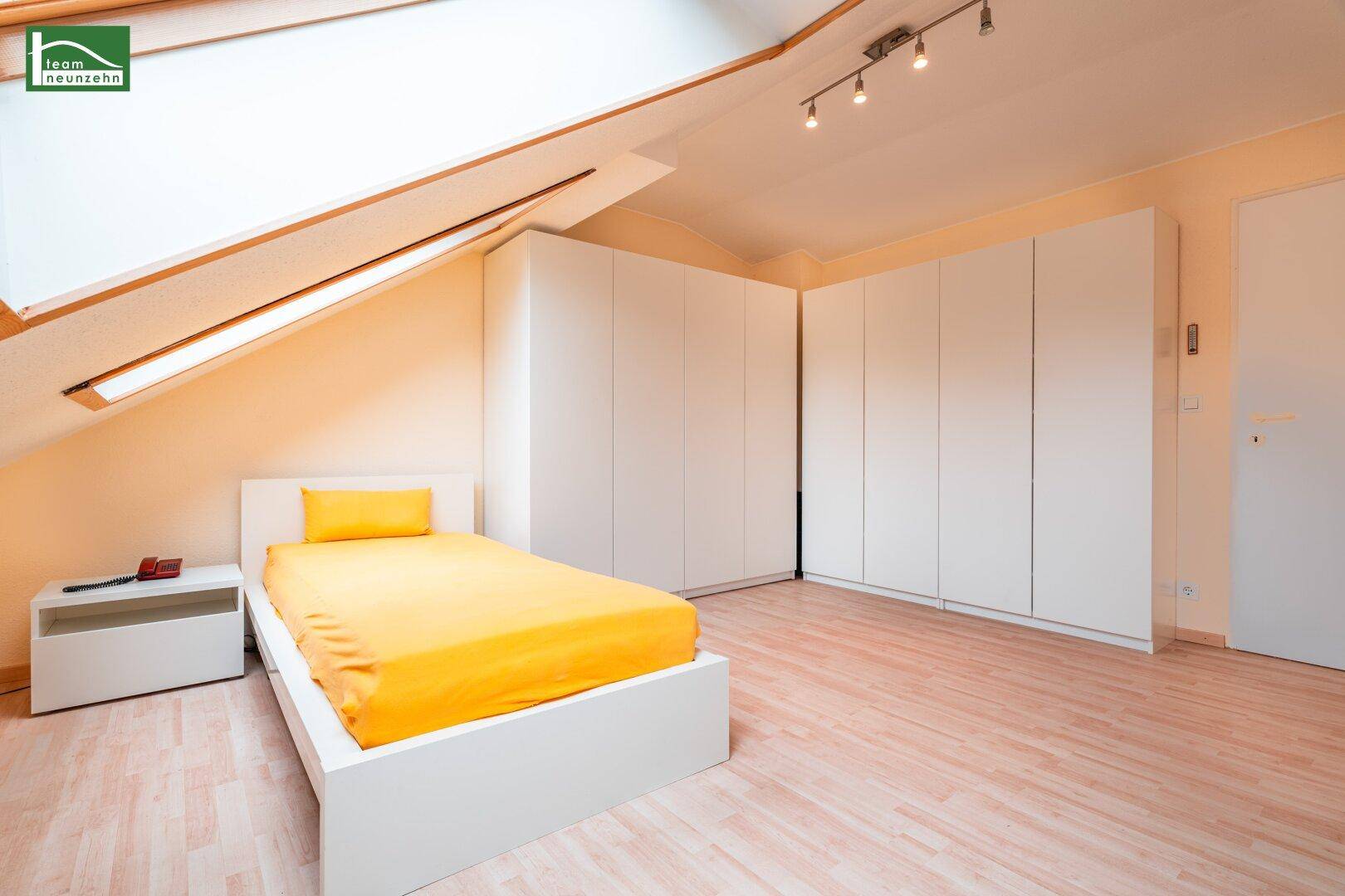 Gemütliches Schlafzimmer im Dachgeschoss mit Einbauschränken, Bett und Dachschräge.