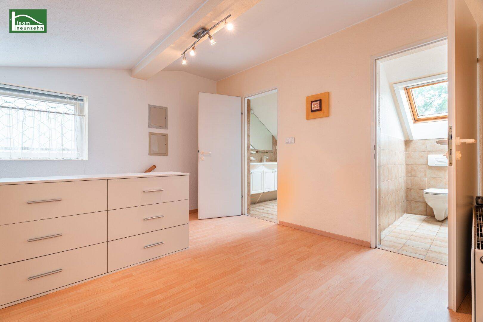Schlafzimmer mit Zugang zu einem gefliesten Badezimmer und separatem WC.