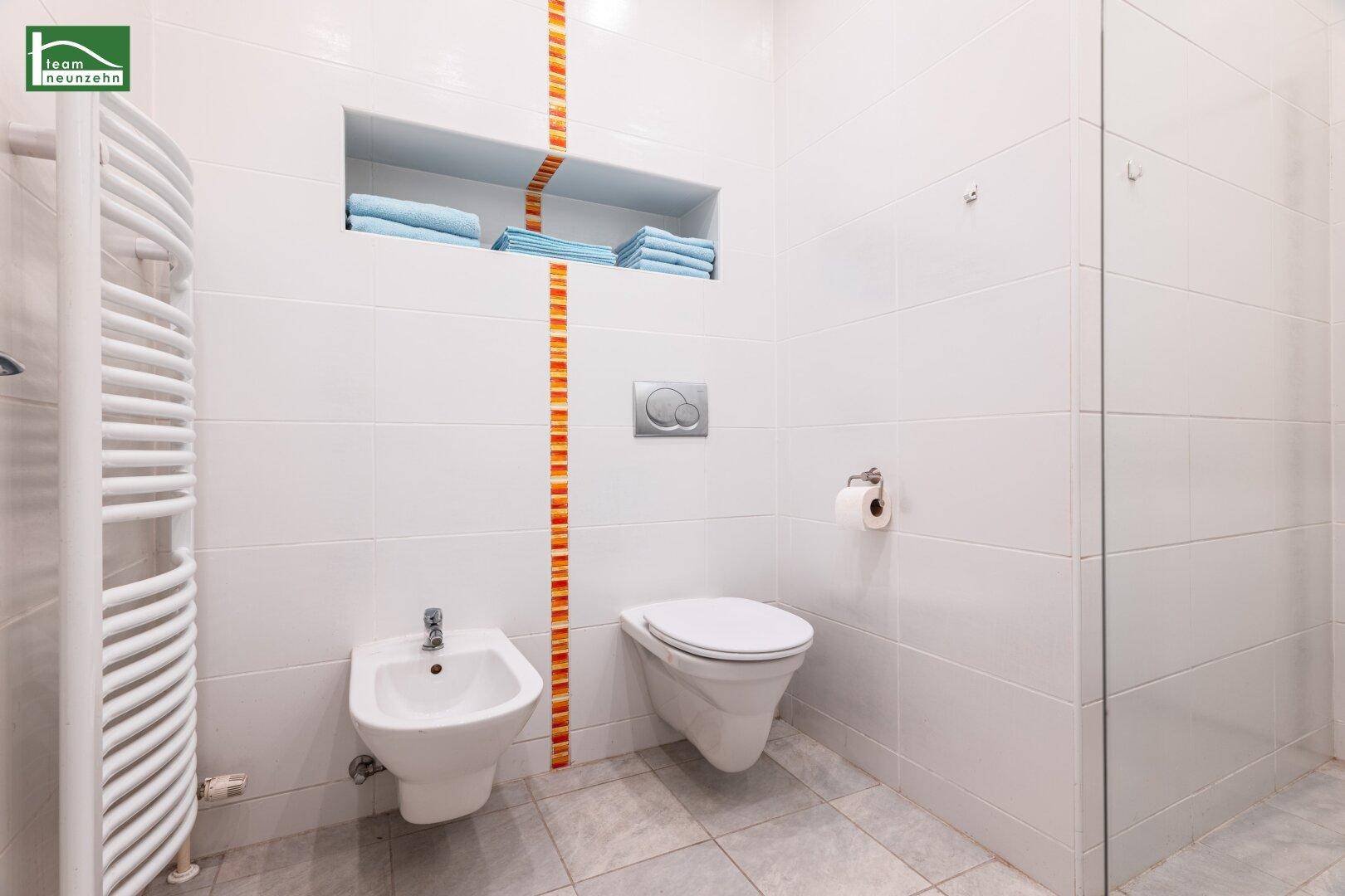 Separates WC mit Bidet, wandhängender Toilette und beheiztem Handtuchhalter in modernem Design.