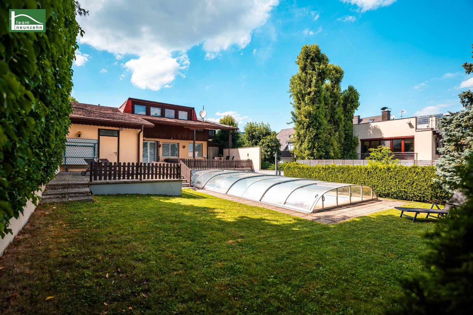 Weitläufiger Gartenbereich mit überdachtem Swimmingpool und gepflegter Rasenfläche hinter dem Haus.