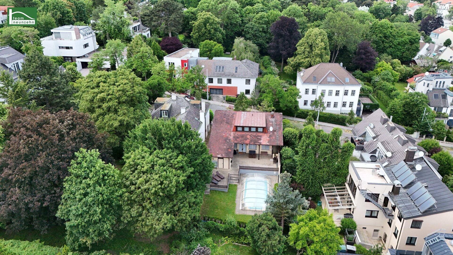 Luftaufnahme des Anwesens mit Haus, Pool und Garten, umgeben von weiteren Wohngebäuden und Bäumen.