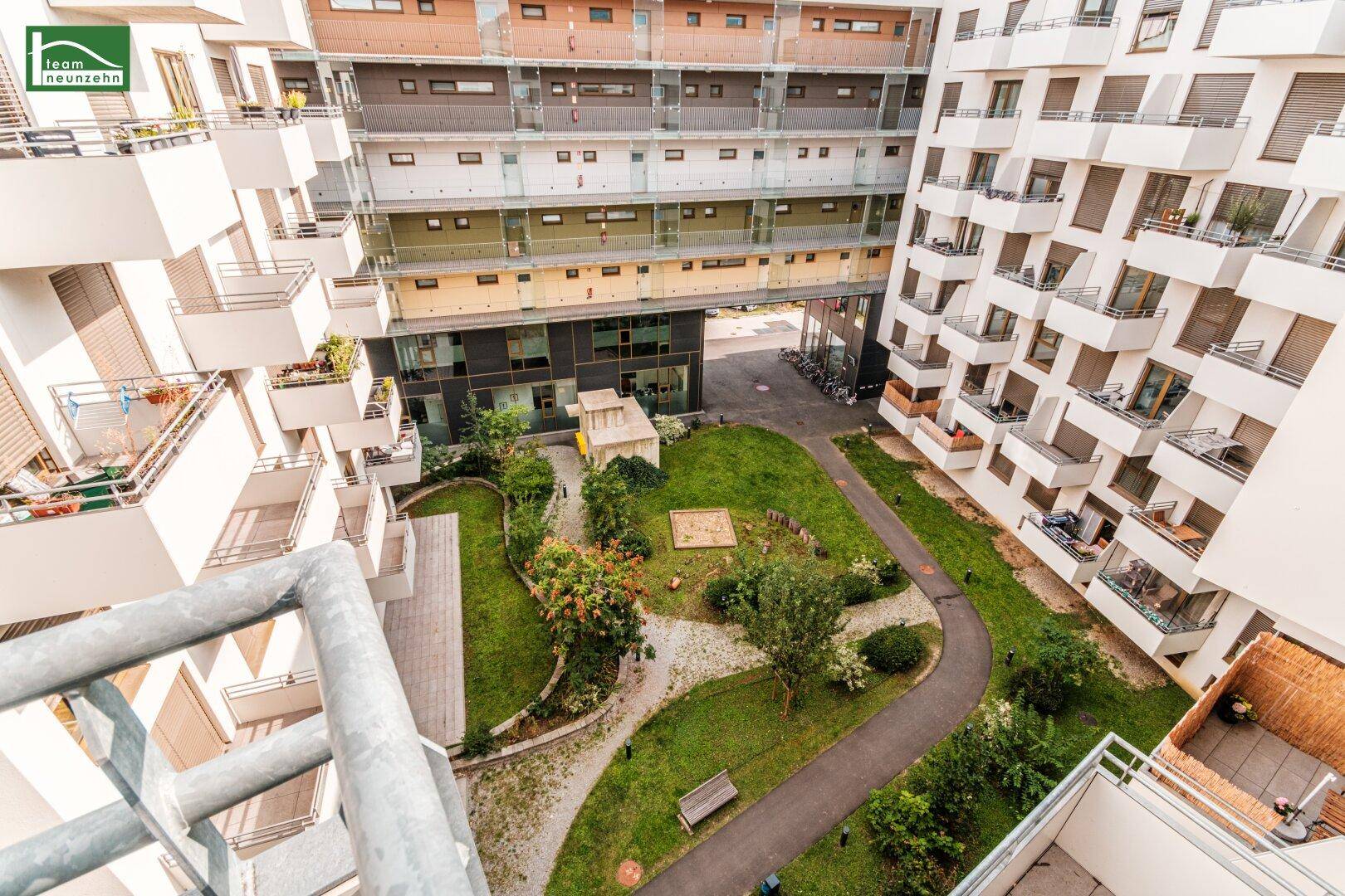 Blick von oben auf einen begrünten Innenhof mit Spielplatz und modernen Wohngebäuden.