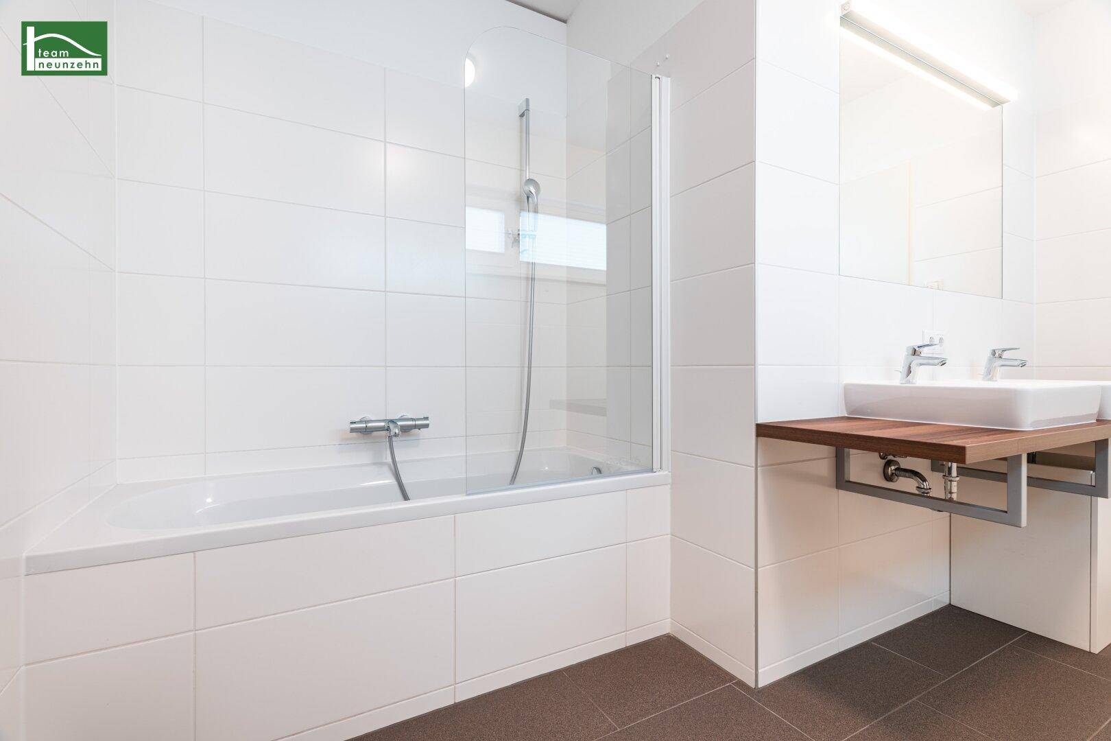 Badezimmer mit Badewanne, Duschabtrennung und modernem Waschbecken.