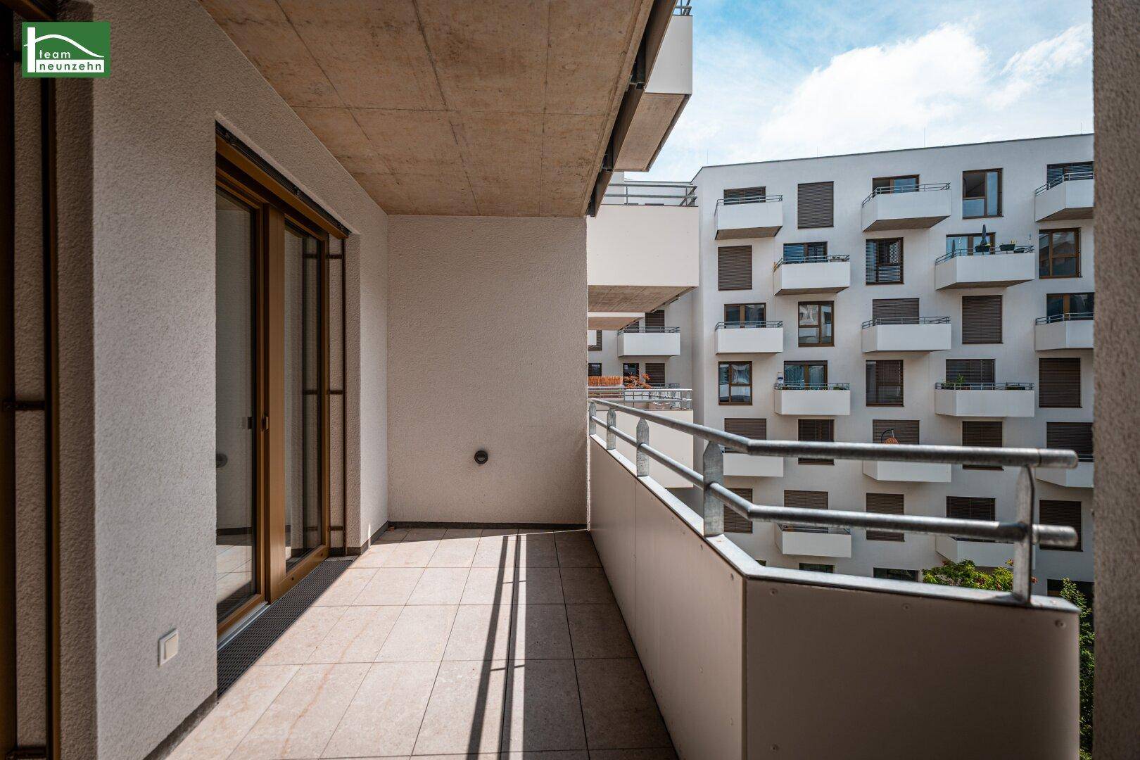 Geräumiger Balkon mit Fliesenboden und Blick auf die umliegenden Gebäude.