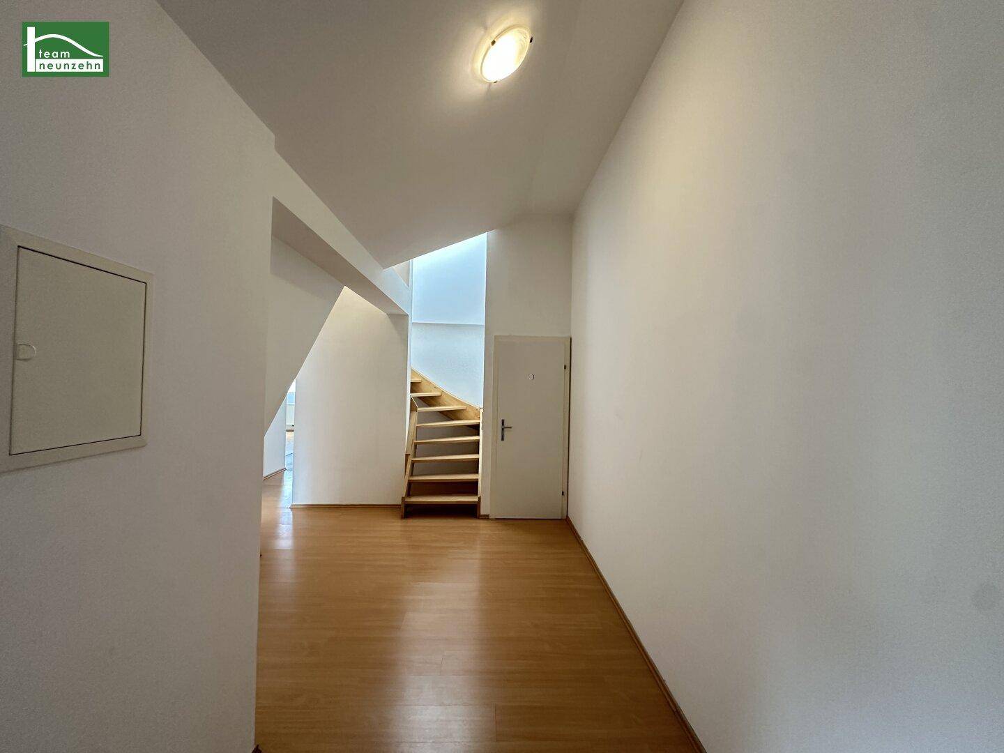 Heller Flur mit Laminatboden und Treppe, die in ein weiteres Stockwerk führt.