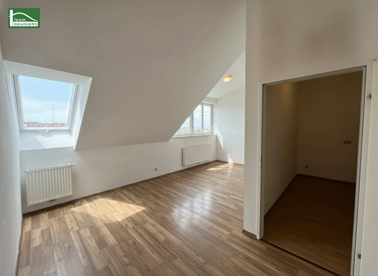Geräumiges Zimmer im Dachgeschoss mit Laminatboden, Dachfenster und Zugang zu einem Abstellraum.