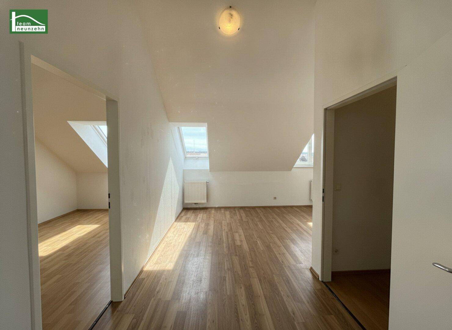 Heller Dachgeschossbereich mit Laminatboden und schrägen Wänden, der mehrere Räume verbindet.