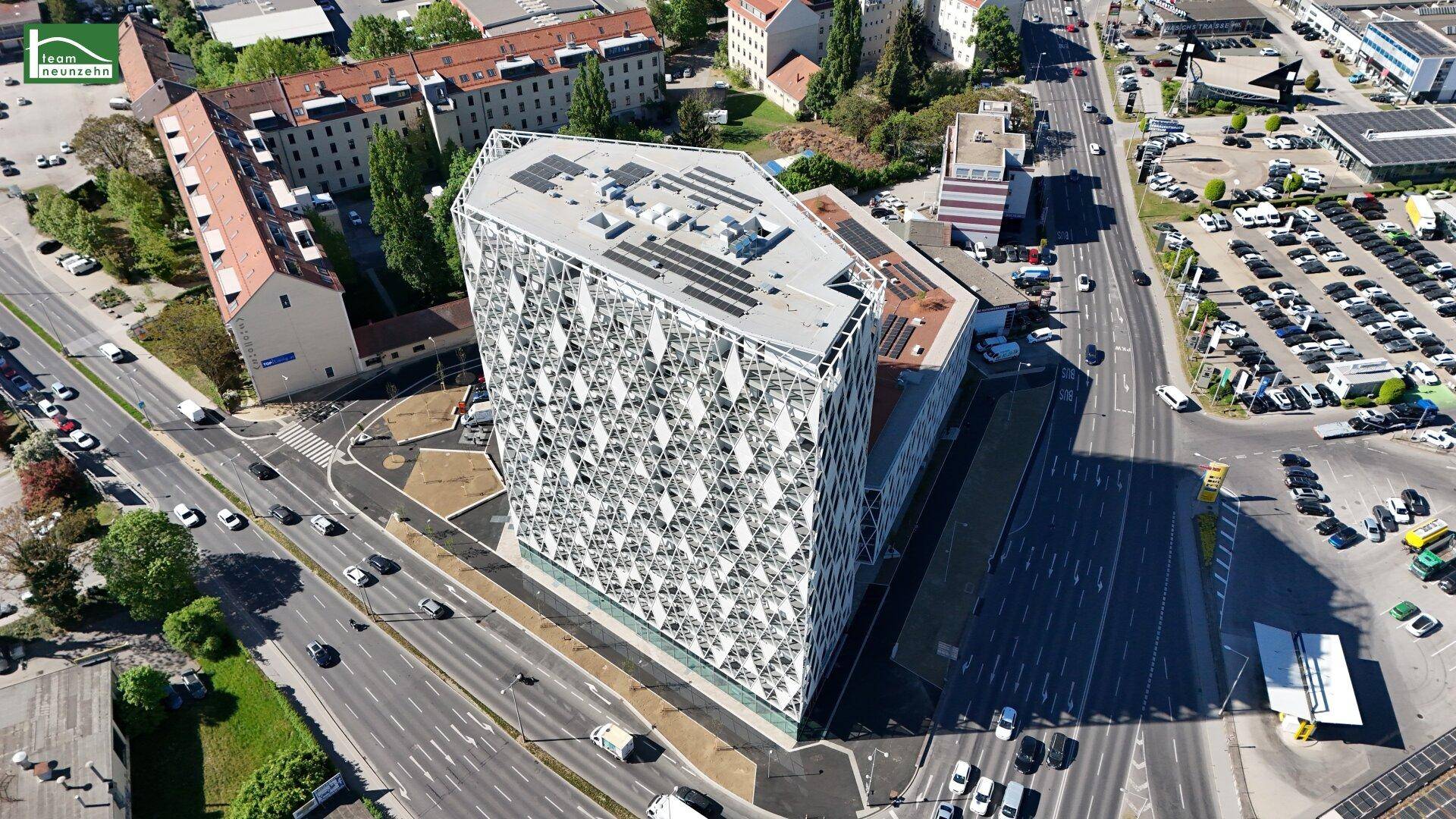 Nahaufnahme aus der Luft des modernen Gebäudes mit markanter Fassade und Solaranlage auf dem Dach.