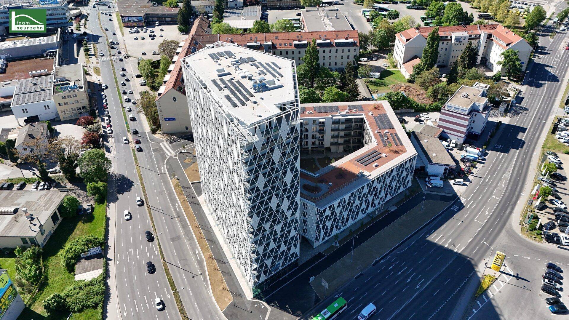 Nahaufnahme des modernen Gebäudes von oben mit geometrischer Fassade und Solaranlagen auf dem Dach.