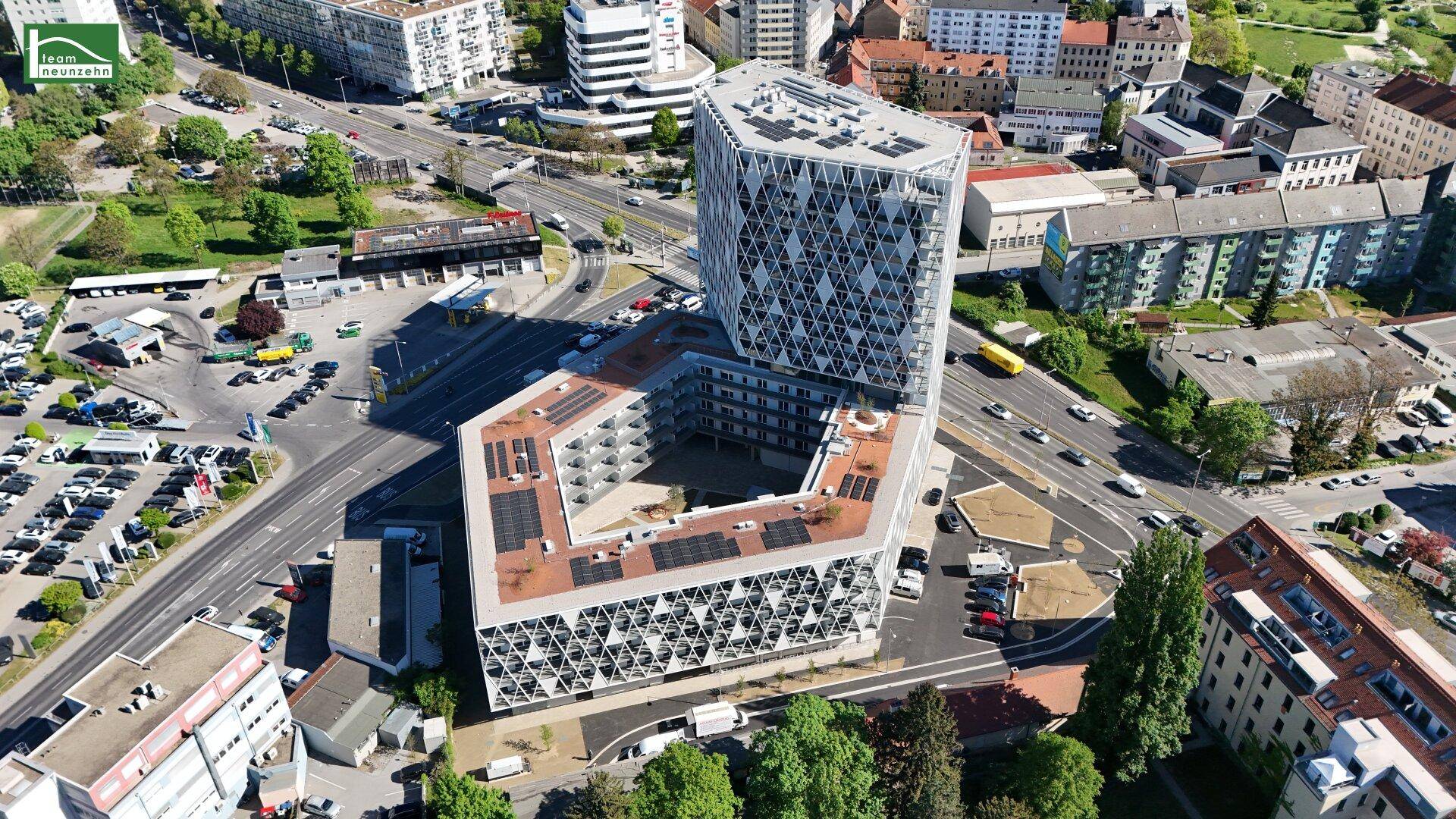 Luftaufnahme eines modernen Gebäudekomplexes mit markanter Fassade in städtischer Umgebung.