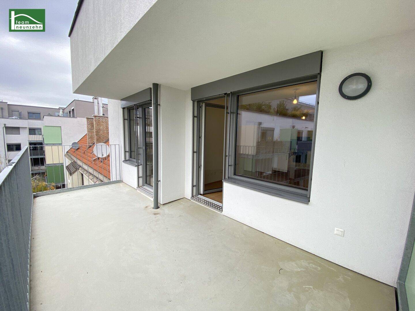 Geräumiger Balkon mit Betonboden und Metallgeländer, bietet Platz für Entspannung im Freien.