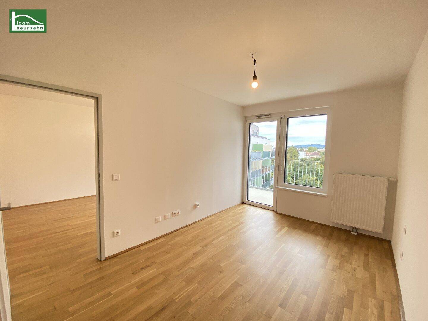 Helles Zimmer mit Parkettboden und Zugang zu einem Balkon, ideal als Schlaf- oder Arbeitszimmer.