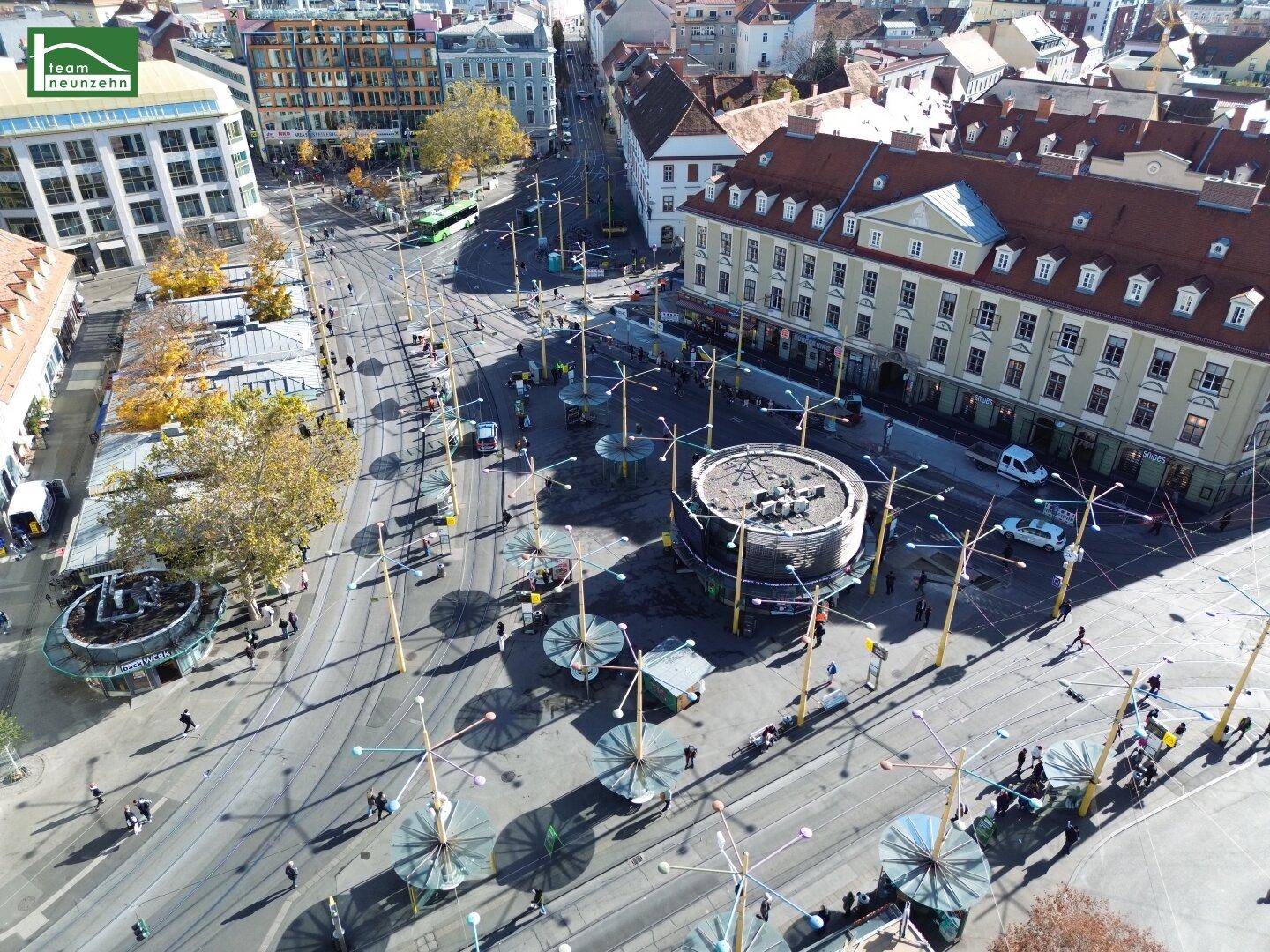 Weitläufiger Stadtplatz aus der Vogelperspektive mit moderner Infrastruktur und historischen Fassaden.