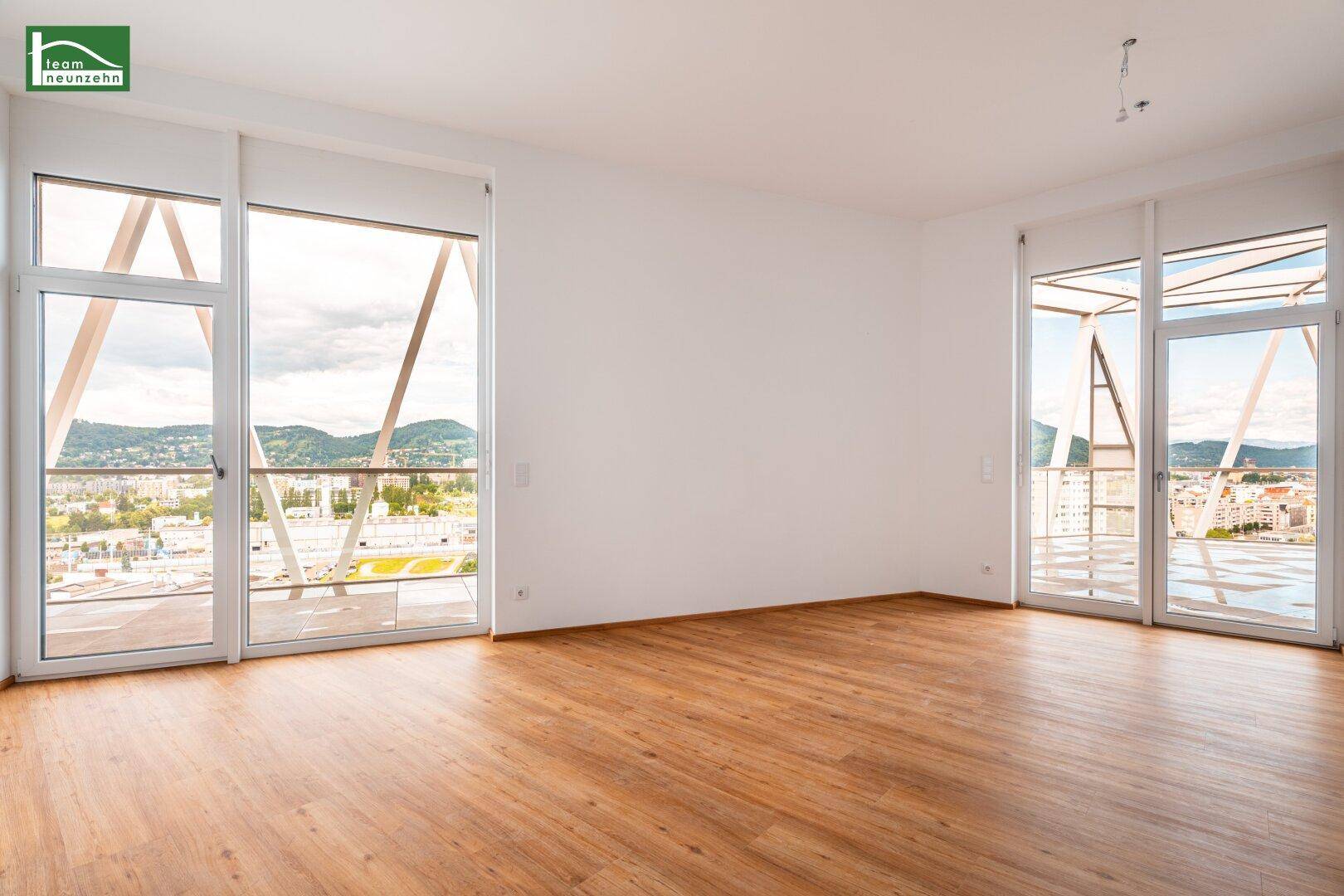 Geräumiges Wohnzimmer mit großen Fenstern und weitem Blick über die Stadtlandschaft.