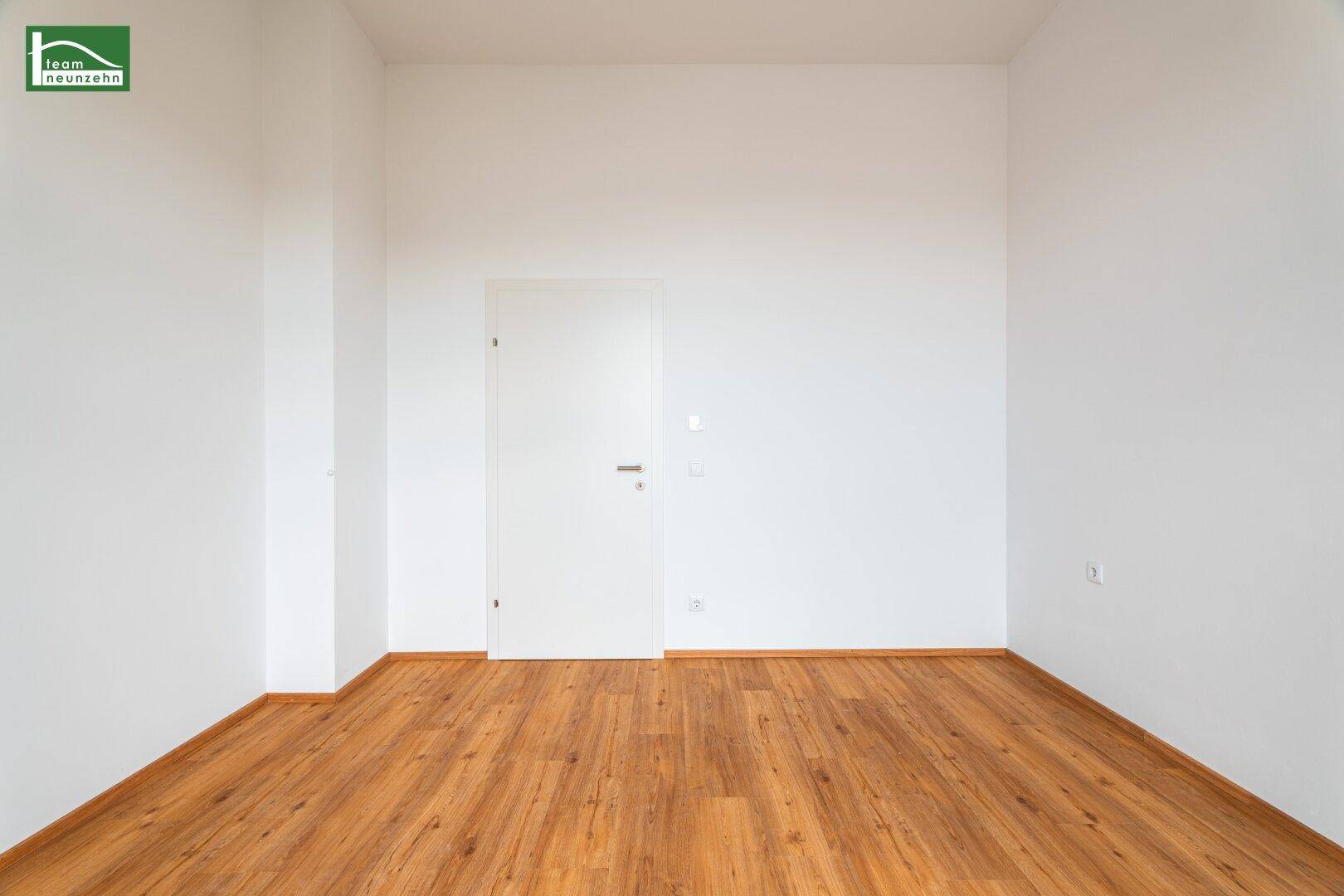 Leeres Schlafzimmer mit Holzboden und weiß gestrichenen Wänden, bereit zur individuellen Gestaltung.