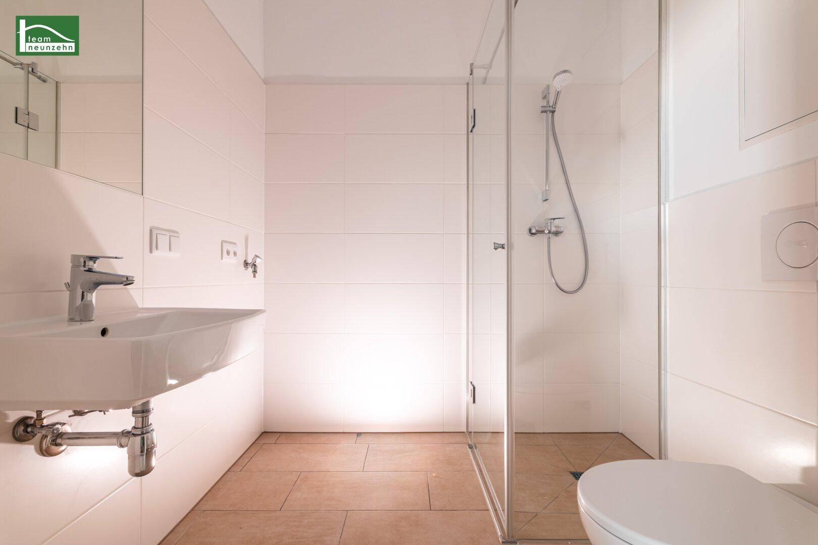 Modernes Badezimmer mit ebenerdiger Dusche, Waschbecken und wandhängendem WC.