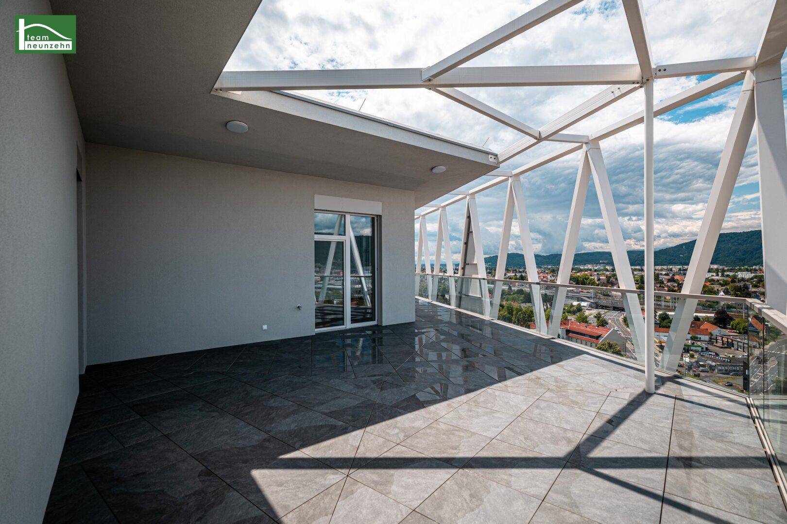 Großer Balkon mit moderner Architektur und weitem Blick über die Stadtlandschaft.