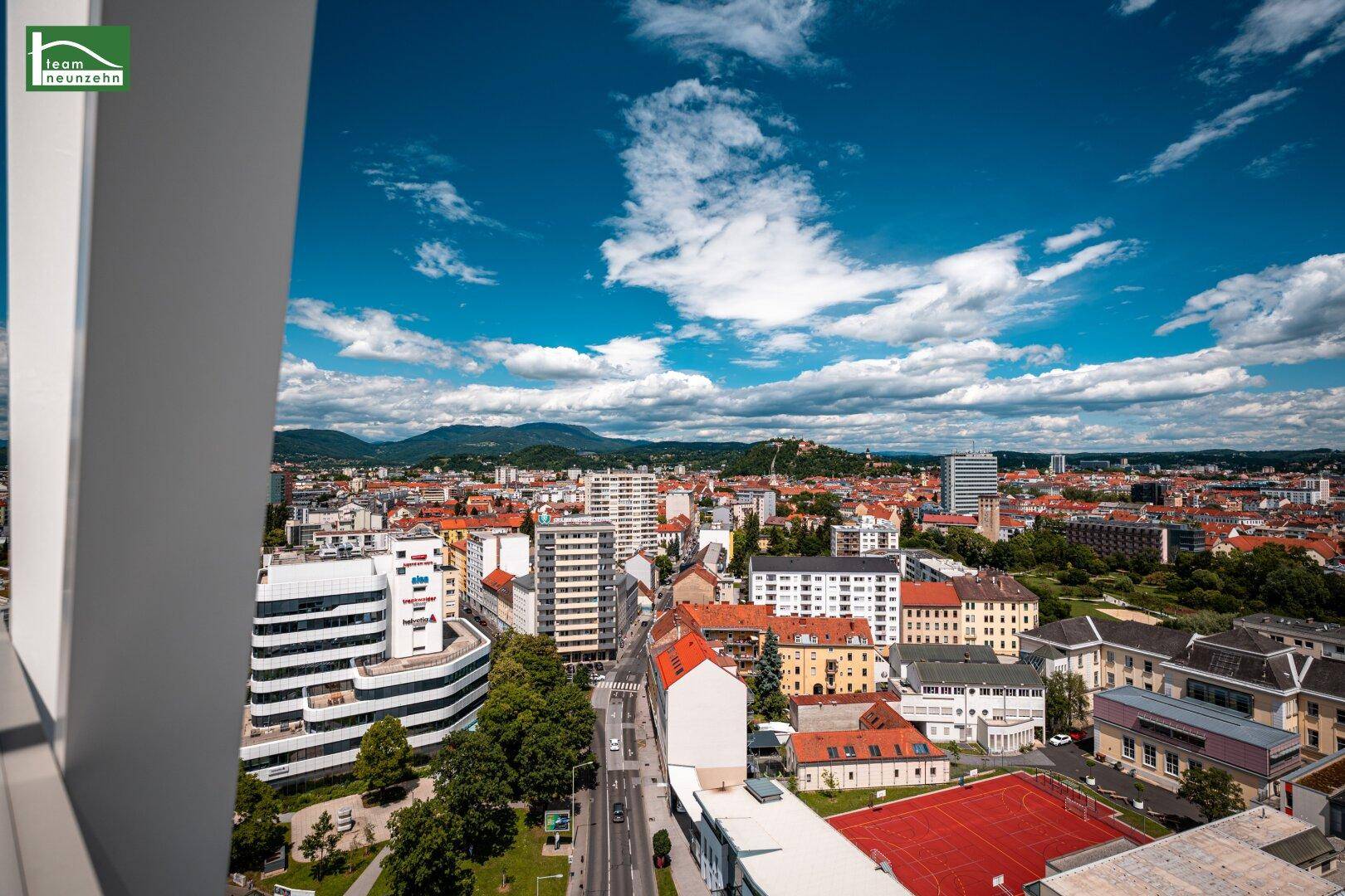 Weitläufiger Blick über die Stadt mit Bergen im Hintergrund und verschiedenen Gebäudetypen.
