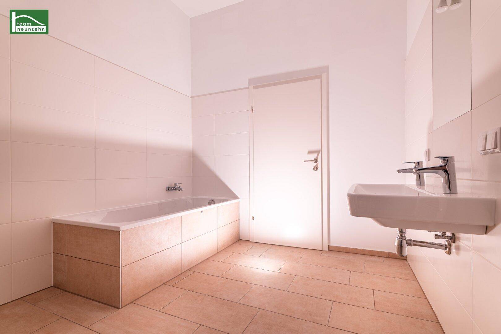Helles Badezimmer mit moderner Badewanne, Waschbecken und großformatigen Fliesen.