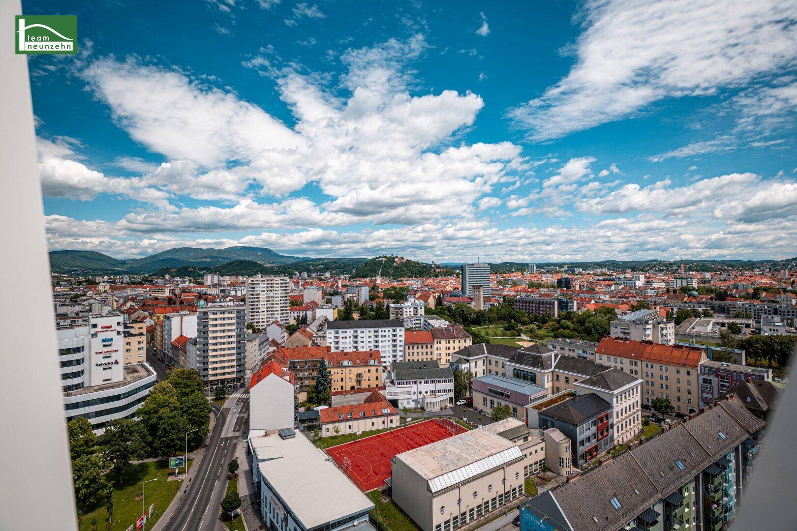 Beeindruckender Ausblick auf die städtische Skyline und die umliegende Natur unter blauem Himmel.