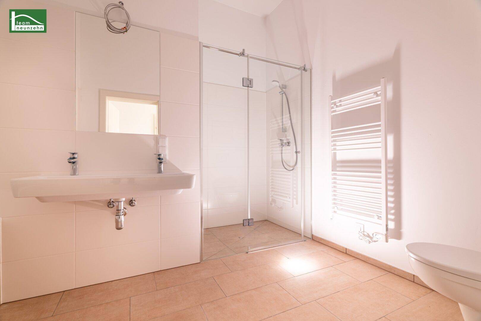 Modernes Badezimmer mit ebenerdiger Dusche, Einzelwaschbecken und beheiztem Handtuchhalter.