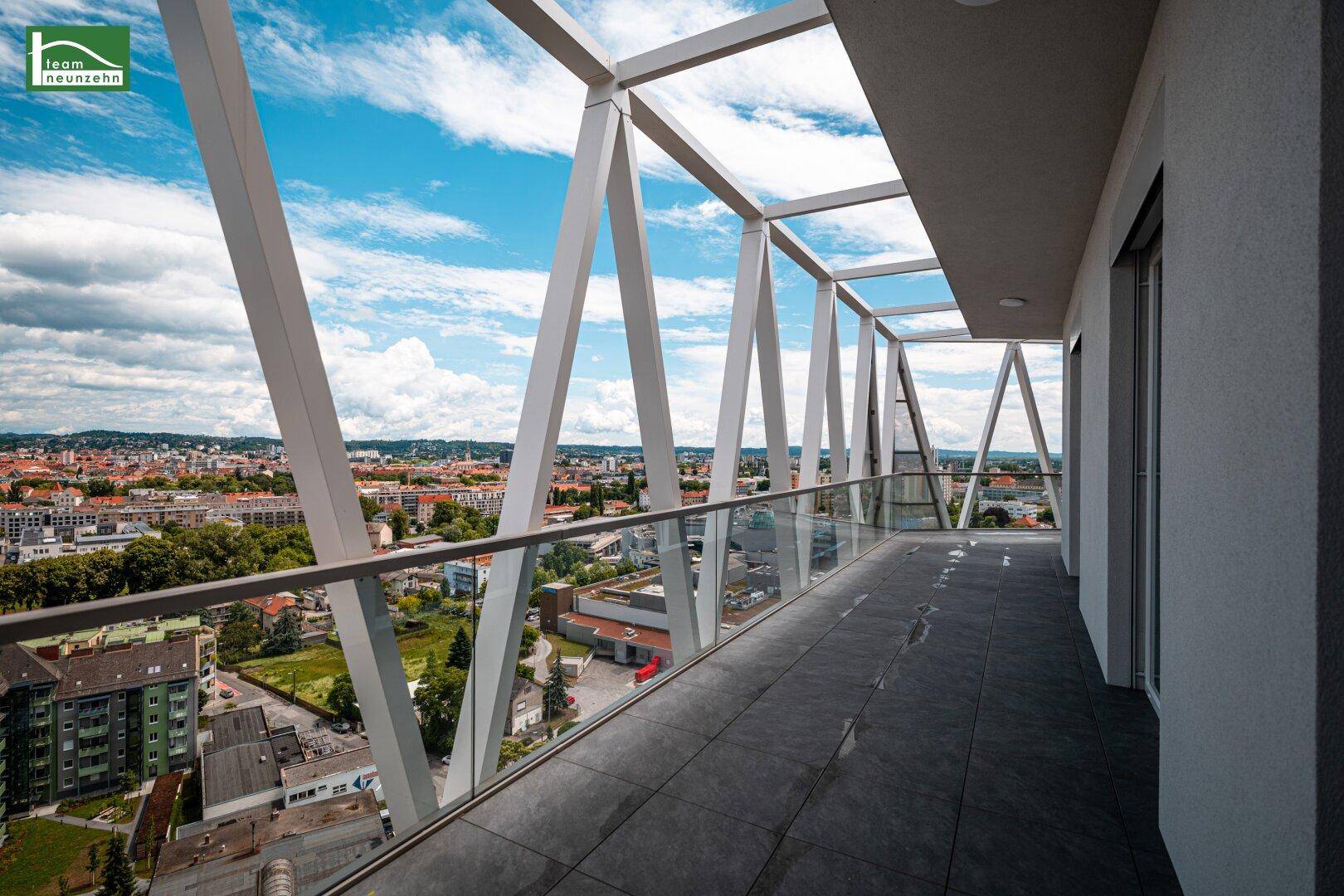 Langer Balkon mit moderner Architektur, Glasgeländer und weitem Blick über die Stadt.
