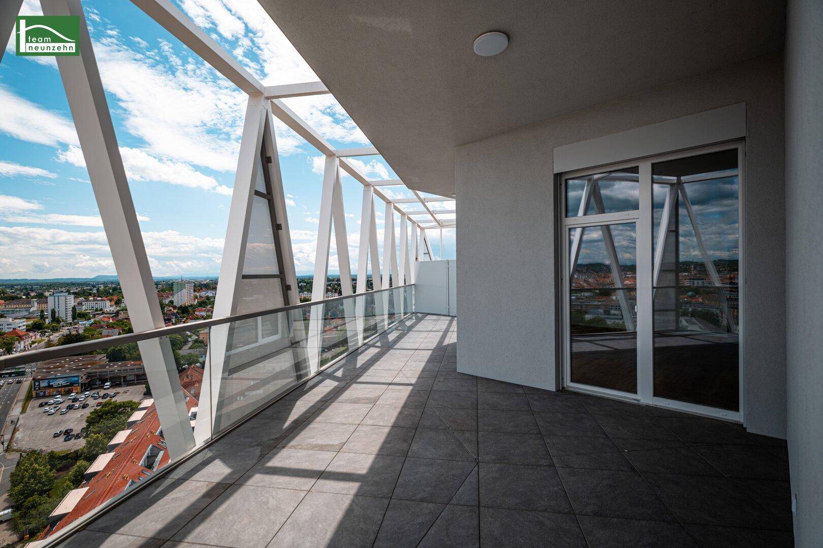 Heller Balkon mit Zugang zum Innenbereich und weitem Blick über die städtische Umgebung.