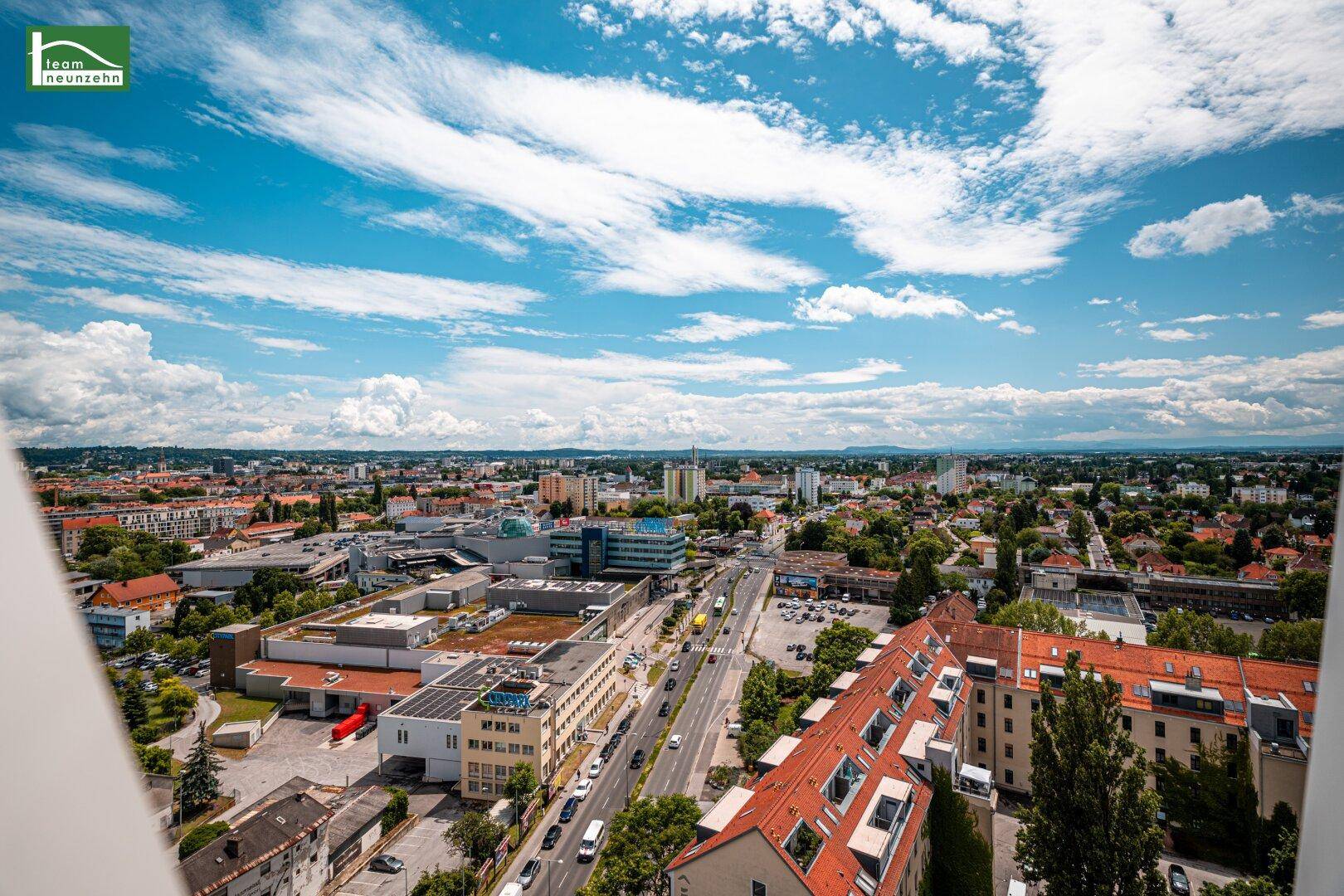 Weiter Blick über die Stadt mit Straßen, Gebäuden und einem klaren blauen Himmel.