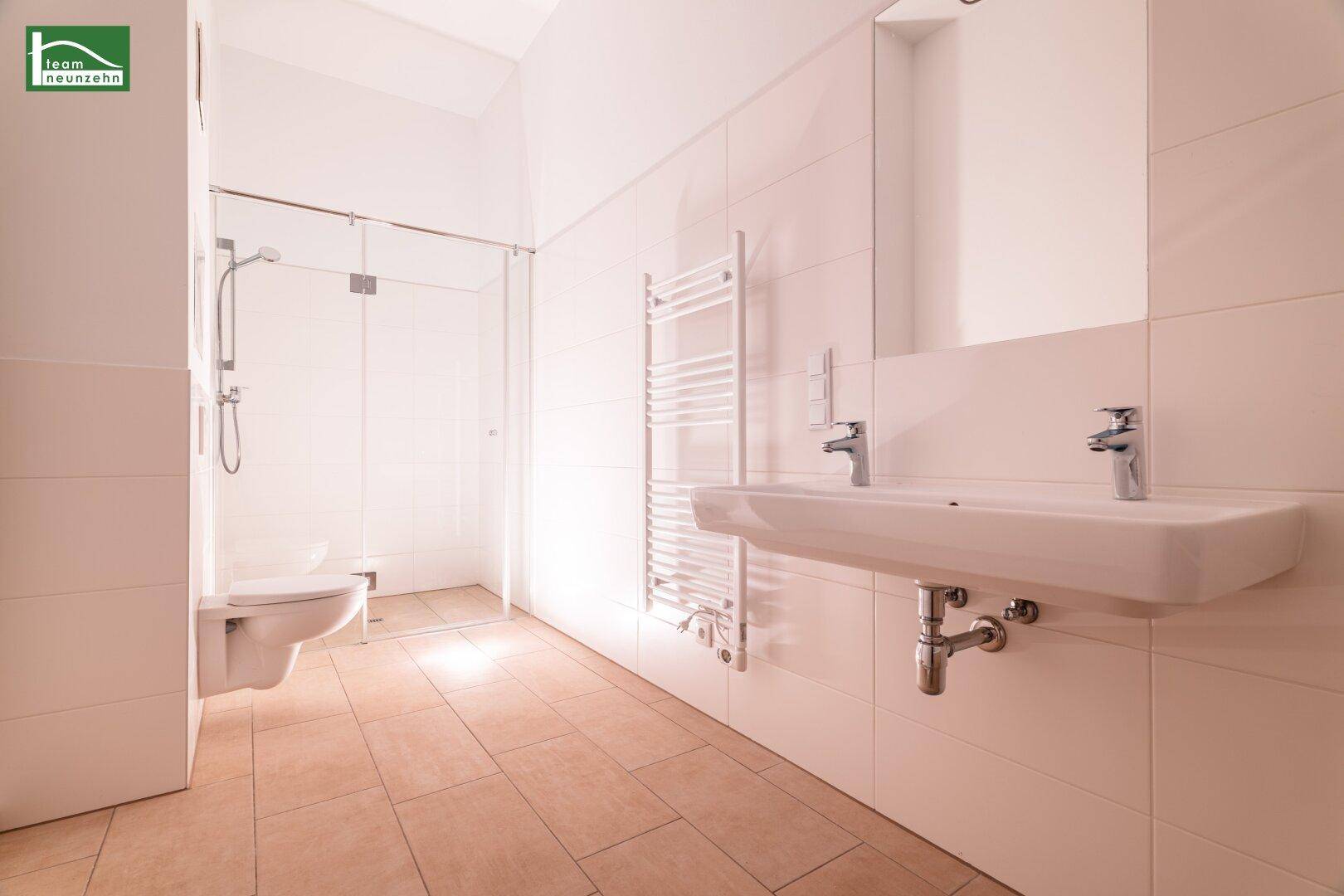 Modernes Badezimmer mit ebenerdiger Dusche, wandhängendem WC und beheiztem Handtuchhalter.