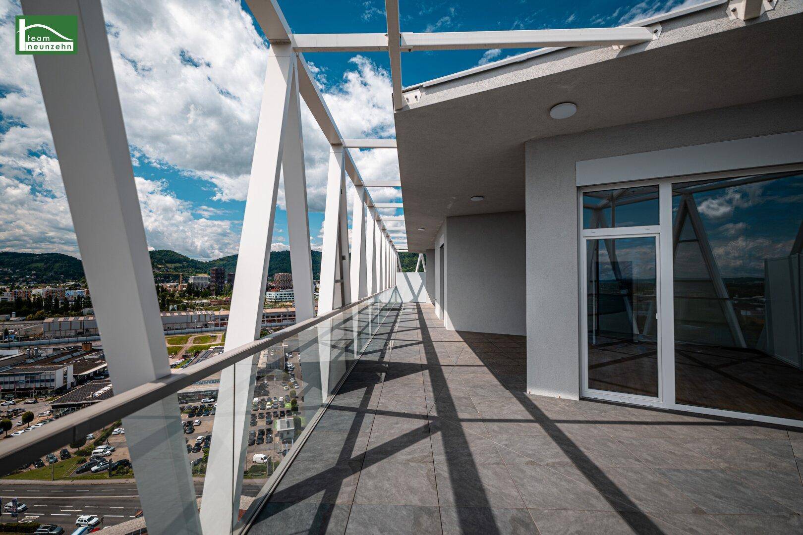 Ausgedehnter Balkon mit moderner Architektur, Glasbrüstung und weitreichendem Blick auf die Stadtlandschaft.