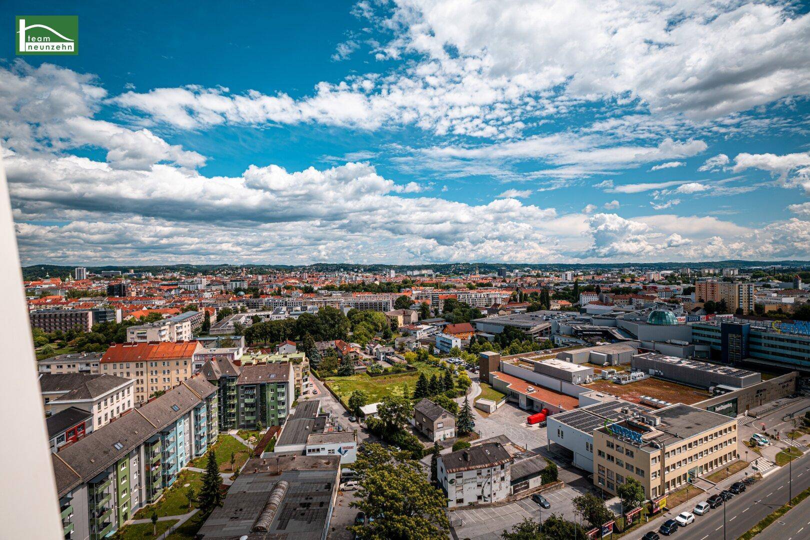 Breiter Ausblick auf die städtische Bebauung und die weite Landschaft unter einem klaren Himmel.