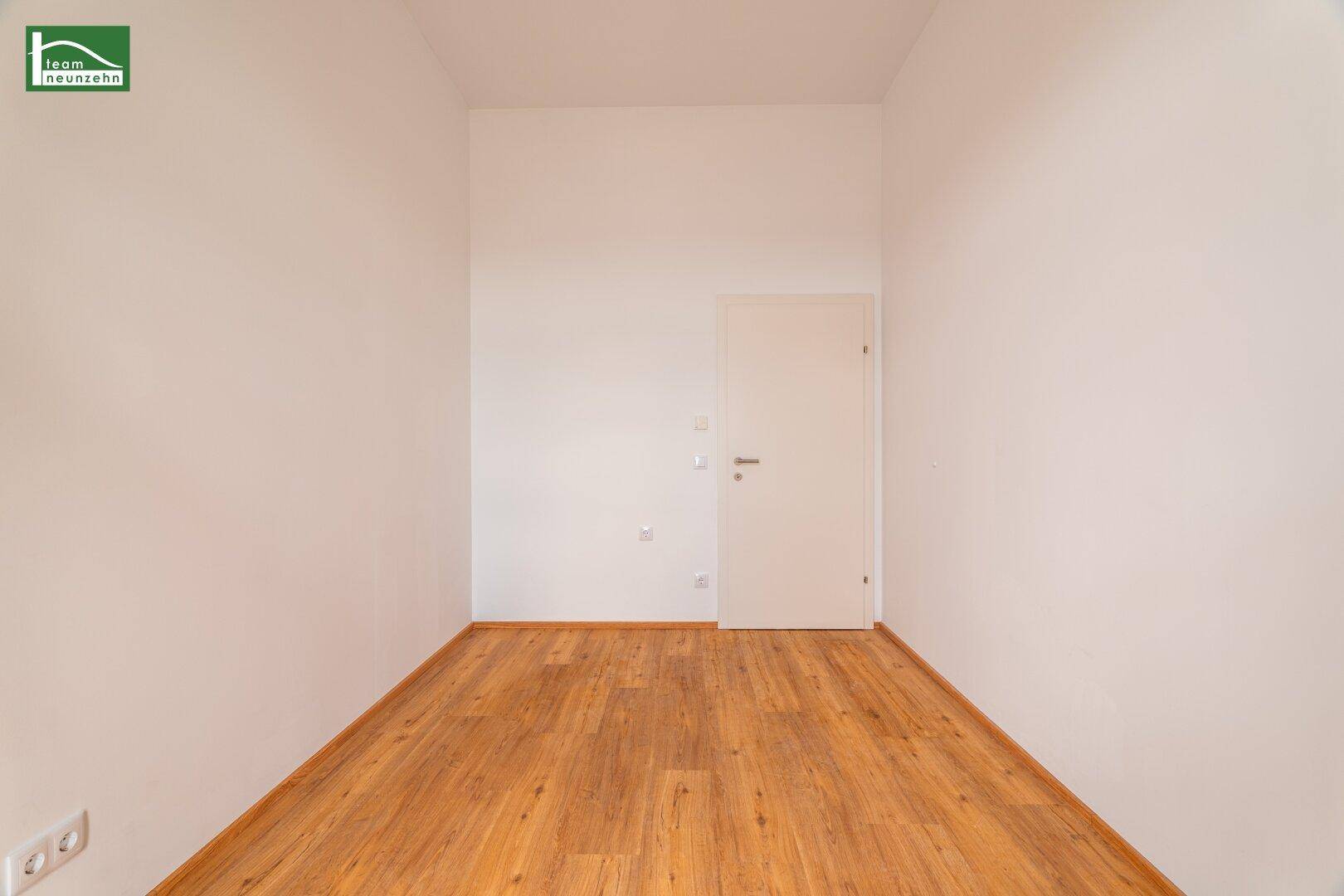 Leerer Raum mit Holzboden und weiß gestrichenen Wänden, bereit zur individuellen Gestaltung.