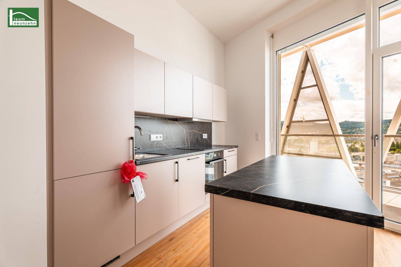 Moderne Küche mit hellen Schränken, dunkler Arbeitsplatte und integrierten Geräten, mit schöner Aussicht.