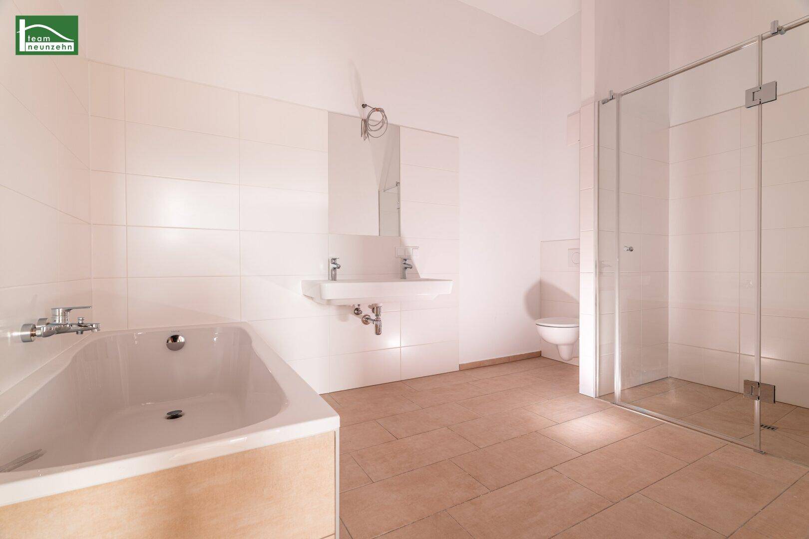 Geräumiges Badezimmer mit Badewanne, Doppelwaschbecken, Toilette und einer modernen begehbaren Dusche.