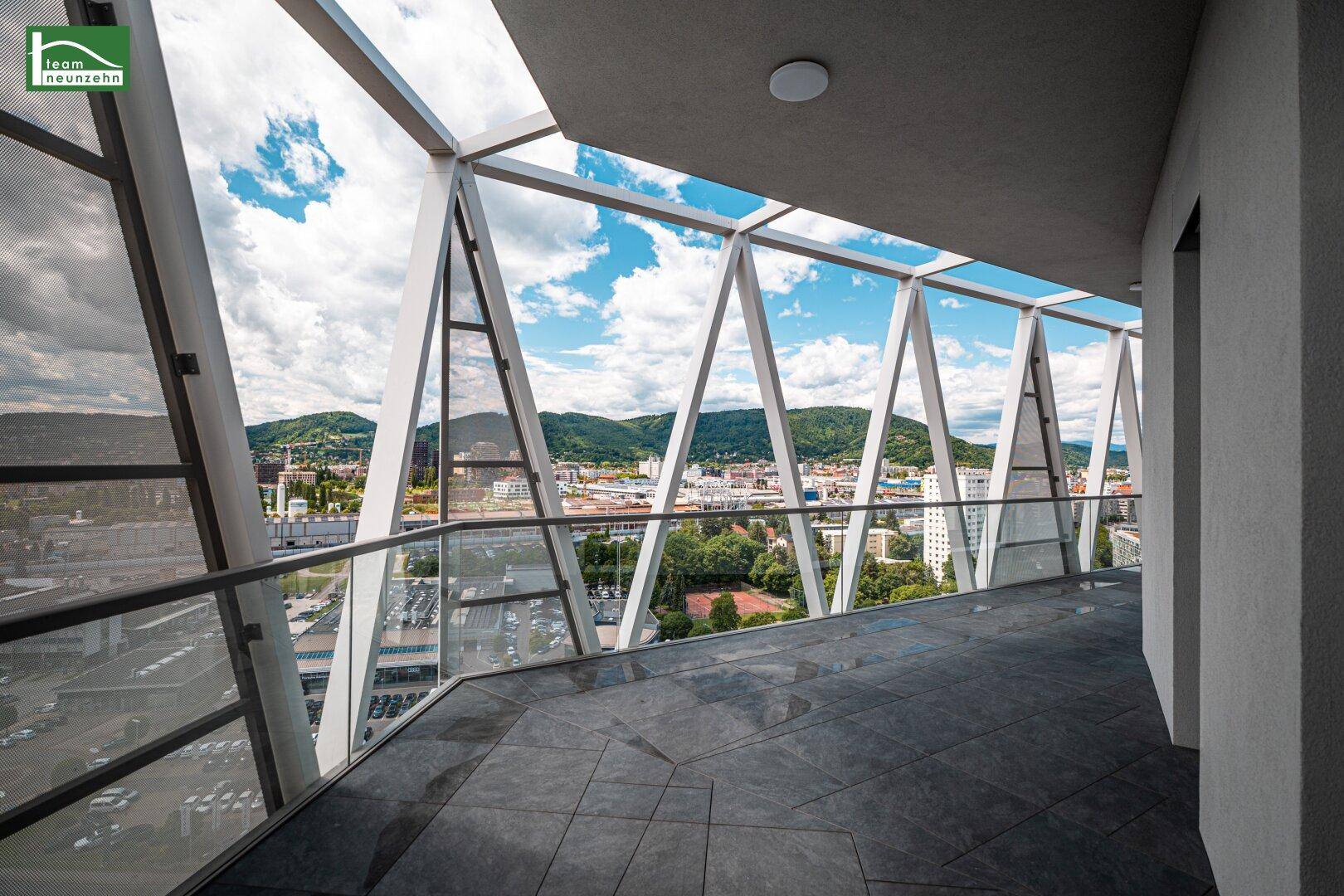 Breiter Balkon mit moderner Glasbrüstung und beeindruckendem Panoramablick auf die Stadt und die umliegende Landschaft.