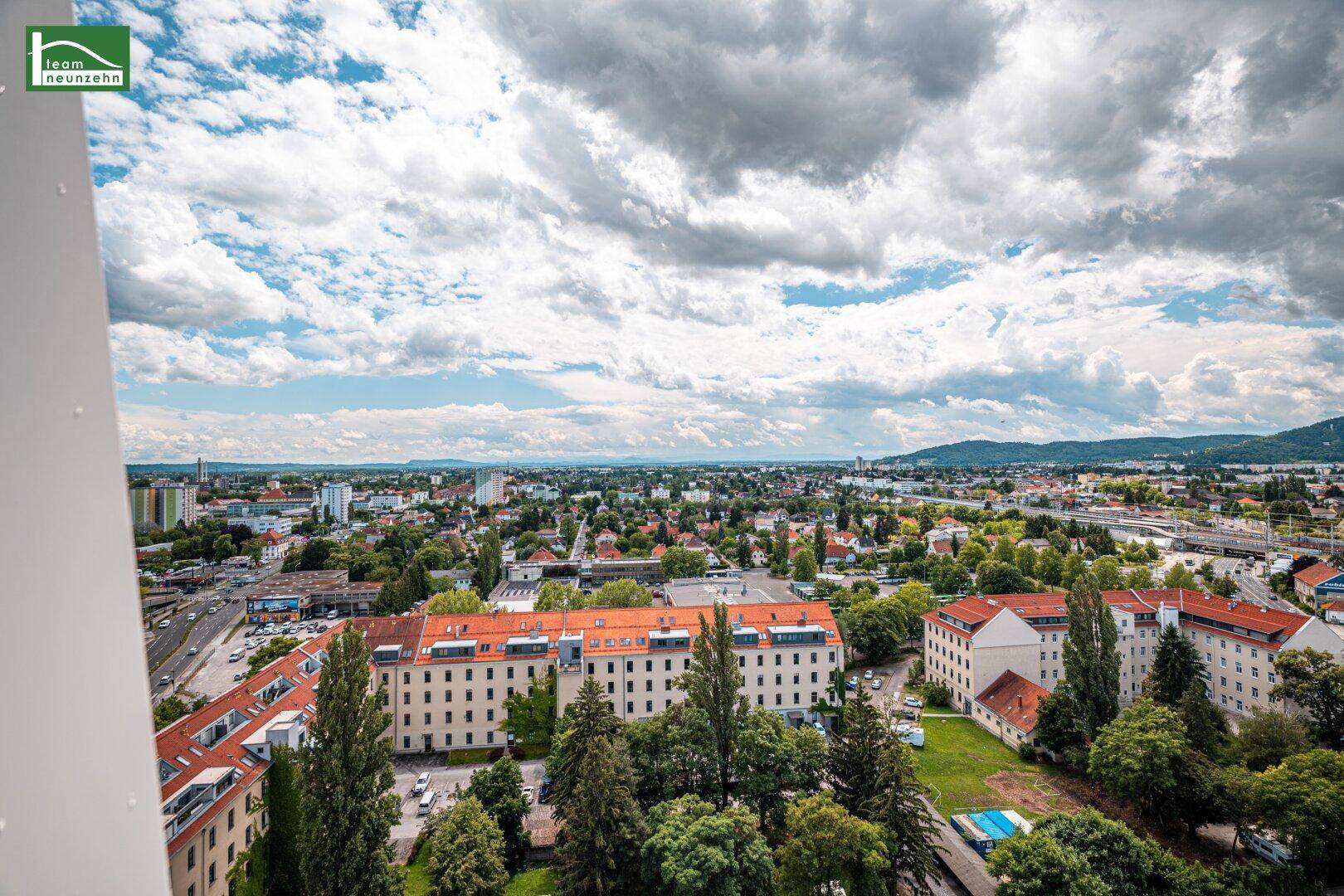 Ausblick über Wohngebiete der Stadt mit viel Grün und einer weiten Landschaft im Hintergrund.