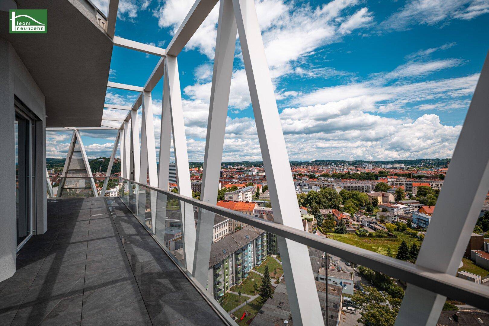 Weiter Blick vom Balkon über die Dächer der Stadt bis zu den fernen Bergen.