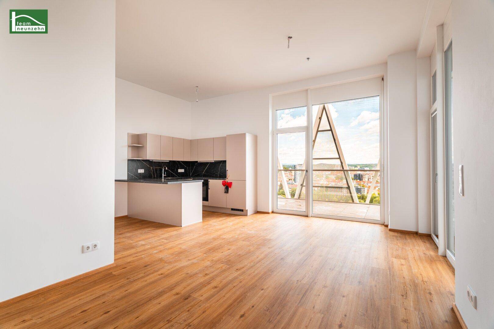 Offener Wohnbereich mit integrierter Küchenzeile, Holzboden und Zugang zur Terrasse.