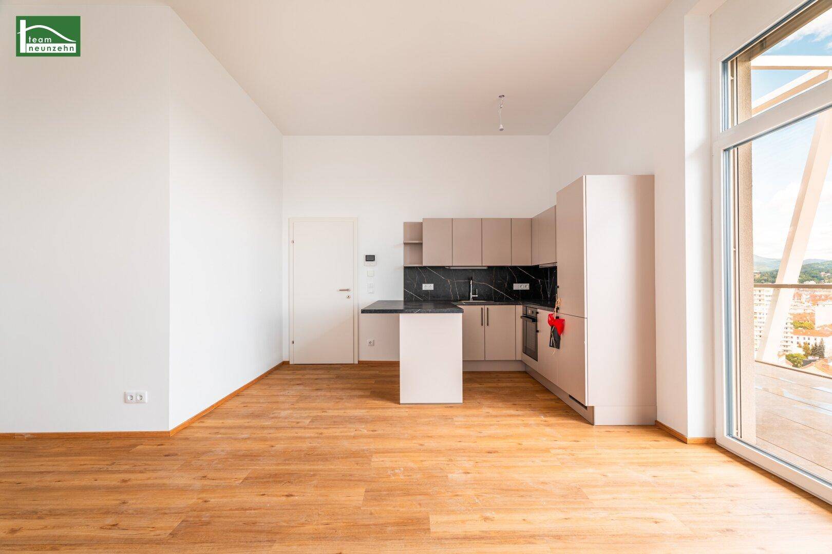 Moderner Wohnbereich mit integrierter Küchenzeile, Holzboden und großen Fenstern.